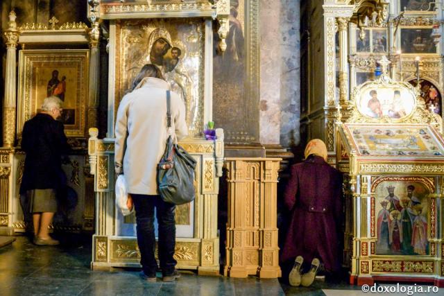credincioși rugându-se în fața icoanelor