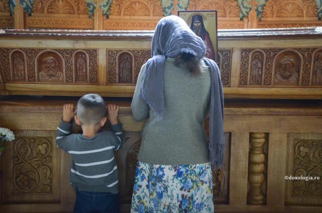femeie și copil rugându-se la racla cu moaștele Sfântului Ioan Iacob de la Neamț