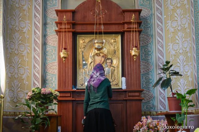 femeie în fața icoanei Maicii Domnului