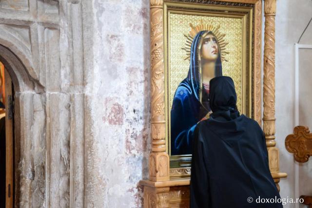 femeie în fața icoanei Maicii Domnului