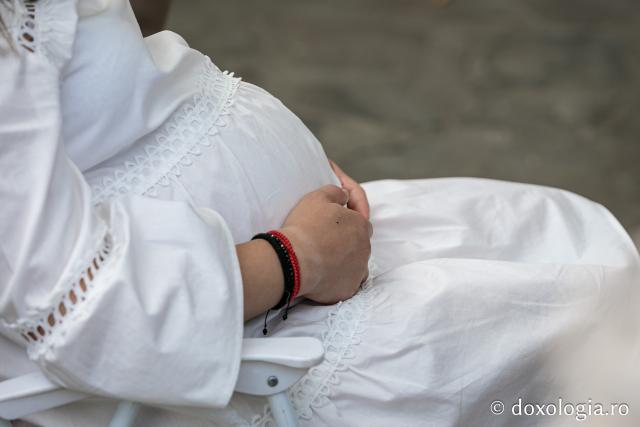 Femeie însărcinată rugându-se la Sfânta Liturghie